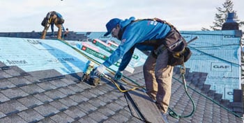 2 roofers installing Timberline Ultra High Definition shingles over the blue synthetic underlayment
