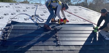 two roofers installing an array of GAF Timberline Solar Energy Shingles on a roof