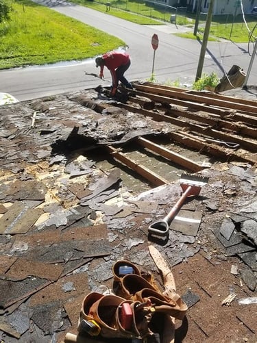 roofer tearing off a roof with rotten plywood decking
