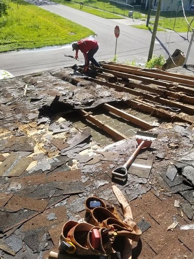 roofer tearing off a roof with rotten plywood decking