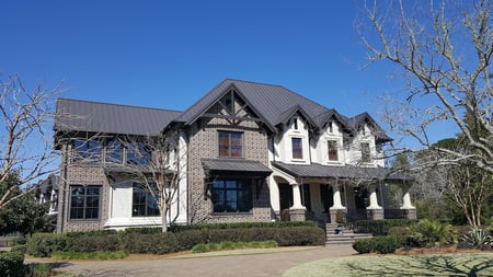Brick and stucco home with brown aluminum standing seam metal roof