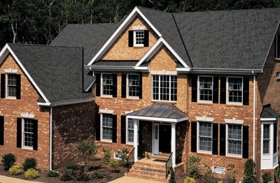 2-story brick home with pewter gray LandMark pro shingles and a copper roof over the front porch