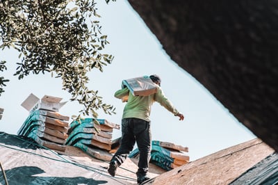 Roofer carrying a bundle of CertainTeed Landmark pro shingles on a roof replacement