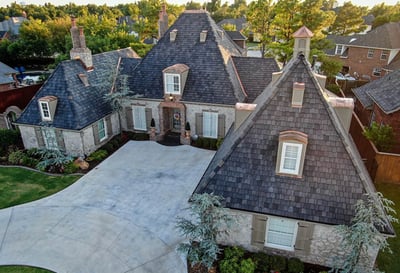 Large brick home with a steel synthetic wood shake roof