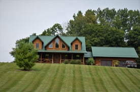 Green metal roof on a farmhouse on a grassy hill