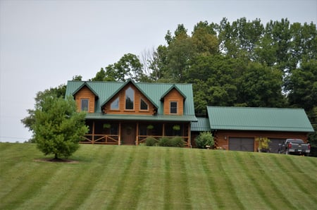 Green metal roof on a farmhouse on a grassy hill