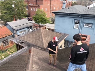 2 roofers inspecting a storm damaged roof