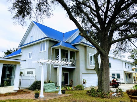 2 story home with bright blue metal roof