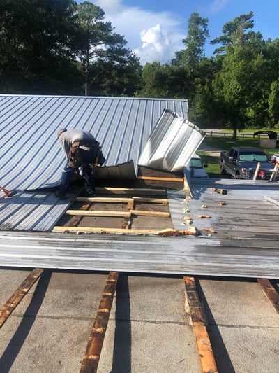 Roofer tearing off a metal roof over shingles