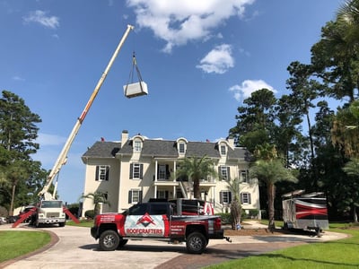 Boom truck hoisting roofing materials to a 4 story roof