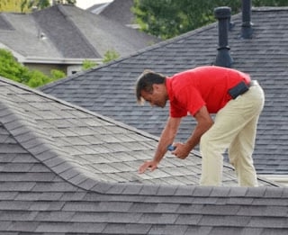 Roofer inspecting an asphalt shingle roof