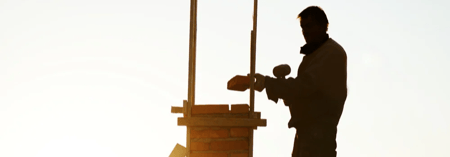 Silhouette of worker building a chimney on a home