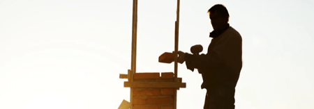 Silhouette of worker building a chimney on a home