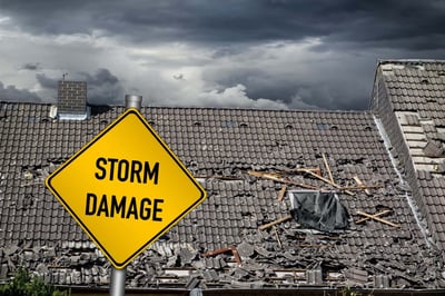 Storm damage sign in front of a tile roof with severe wind damage