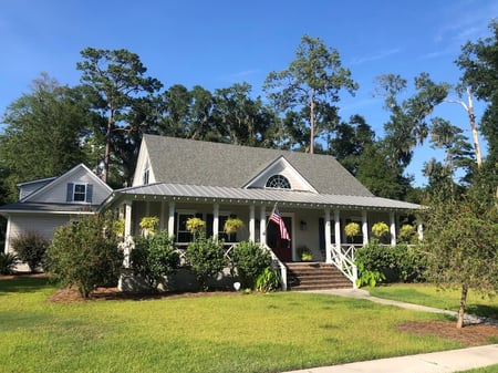 home with a shingle roof that has a wrap-around porch with a metal accent roof