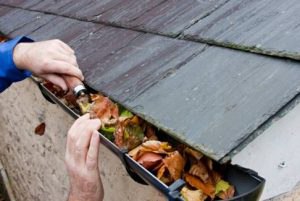 roofer cleaning out gutters full of leaves and debris