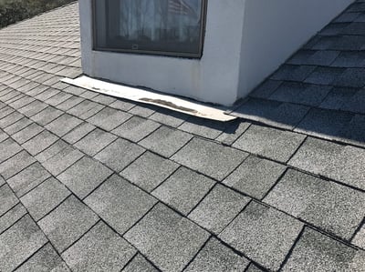 a dormer on a shingle roof with loose flashing