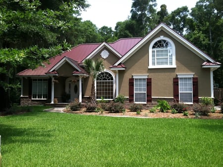 beige stucco home with cultured stone and burgundy standing seam metal roof