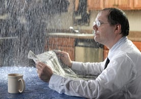 homeowner sitting inside getting rained on from a roof leak