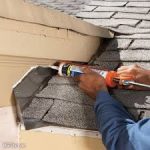 roofer caulking a roof-to-wall flashing detail