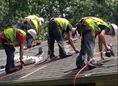 roofers installing a shingle roof with safety gear on