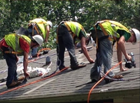 roofers installing a shingle roof with safety gear on