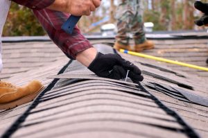 roofer installing shingle over ridge vent on a roof