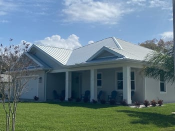 Galvalume standing seam metal roof with hips and valleys on a stucco home with a 2 car garage