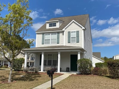 two-story cottage style home with porch and dormers