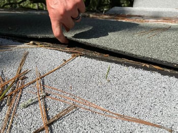 roofer inspecting a failing mod-bit roof