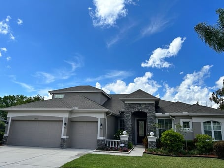 Gray stucco home with cultured stone accents and GAF weatherwood shingles, blend color scheme