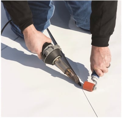 roofer welding seam on a TPO roof with a hand welder