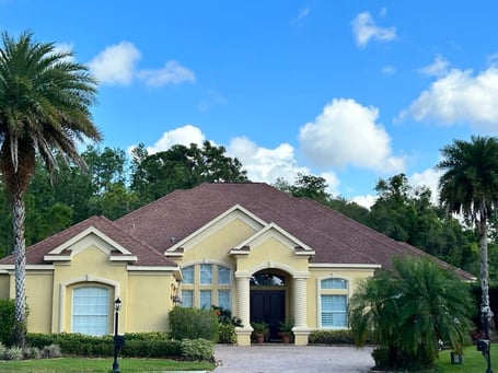 Yellow stucco home with GAF sunset brick red shingles