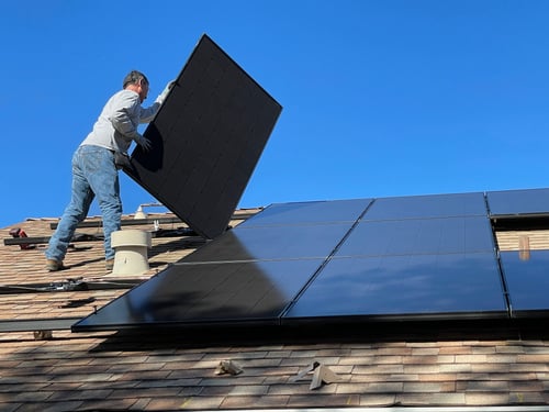 man installing solar panel on roof