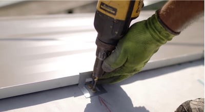 Concealed fastener being installed on standing seam metal roof