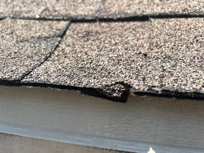 cracked shingle at a roof edge from hail damage