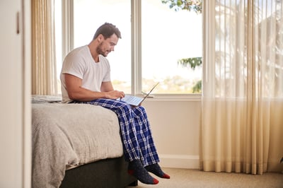 man sitting on a bed relaxing on the computer