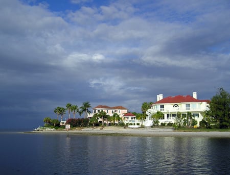 water front home with clay tile roof
