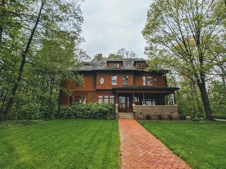 2-story house on a hill surrounded by trees