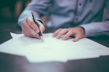 man sitting at a table signing paperwork
