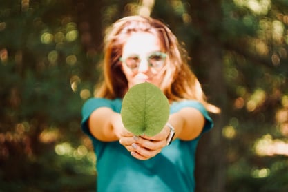 girl holding leaf in wooded area