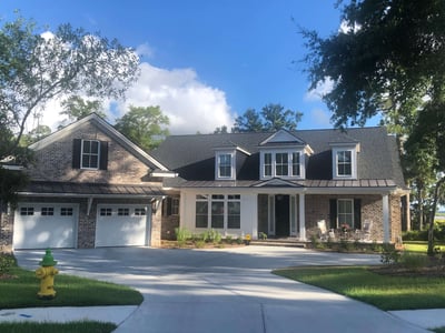 brick home with a black shingle roof with black metal accents