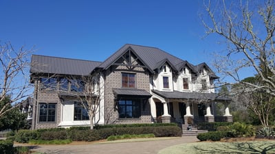 brick and stucco 2 story home with brown metal roof