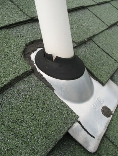 old galvanized metal pipe boot flashing with rotten rubber gasket on green shingles