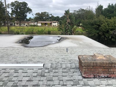 ponding water on a flat roof off the back of a home