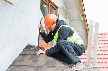 a roofer repairing metal flashing on a shingle roof
