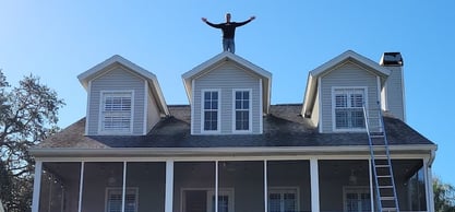 Roofer on top of a dormer on a 2-story home