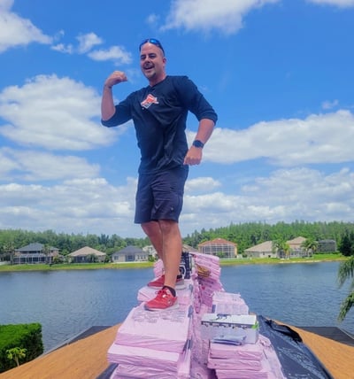 roofer on a stack of shingles on the ridge of a roof