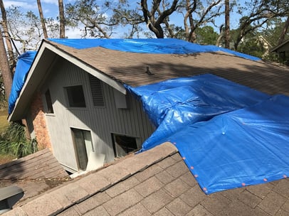 blue tarp on a storm damaged roof