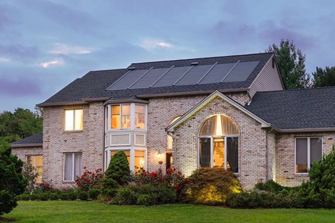 beautiful brick house with solar shingles on the roof